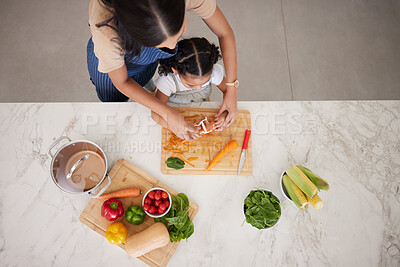 Buy stock photo Cooking, vegetables and mom with child in kitchen cutting, peeling and prepare food. Child development, helping hands and aerial view of mother teaching girl to cook, chef skills and bond together