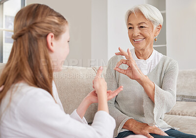 Buy stock photo Senior woman, sign language and deaf girl communication, talking or conversation in home. Support, care and retired old female speaking to child with hearing disability in asl language hand gestures.