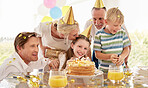 Girl, birthday cake and family celebrating a children event with food and a party outdoor. Happy smile of kids, father and mom kiss to celebrate youth and kid event with happiness, love and confetti