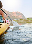 Woman rowing a kayak or boat on a river or lake while on summer vacation or travel. Tourist explore nature on water during a tropical adventure kayaking in the wildlife on summer holiday or vacation
