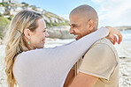 Couple, love and hug on the beach smile for romantic date, anniversary or engagement announcement. Happy people show commitment care, happiness and trust by the sea and ocean water together