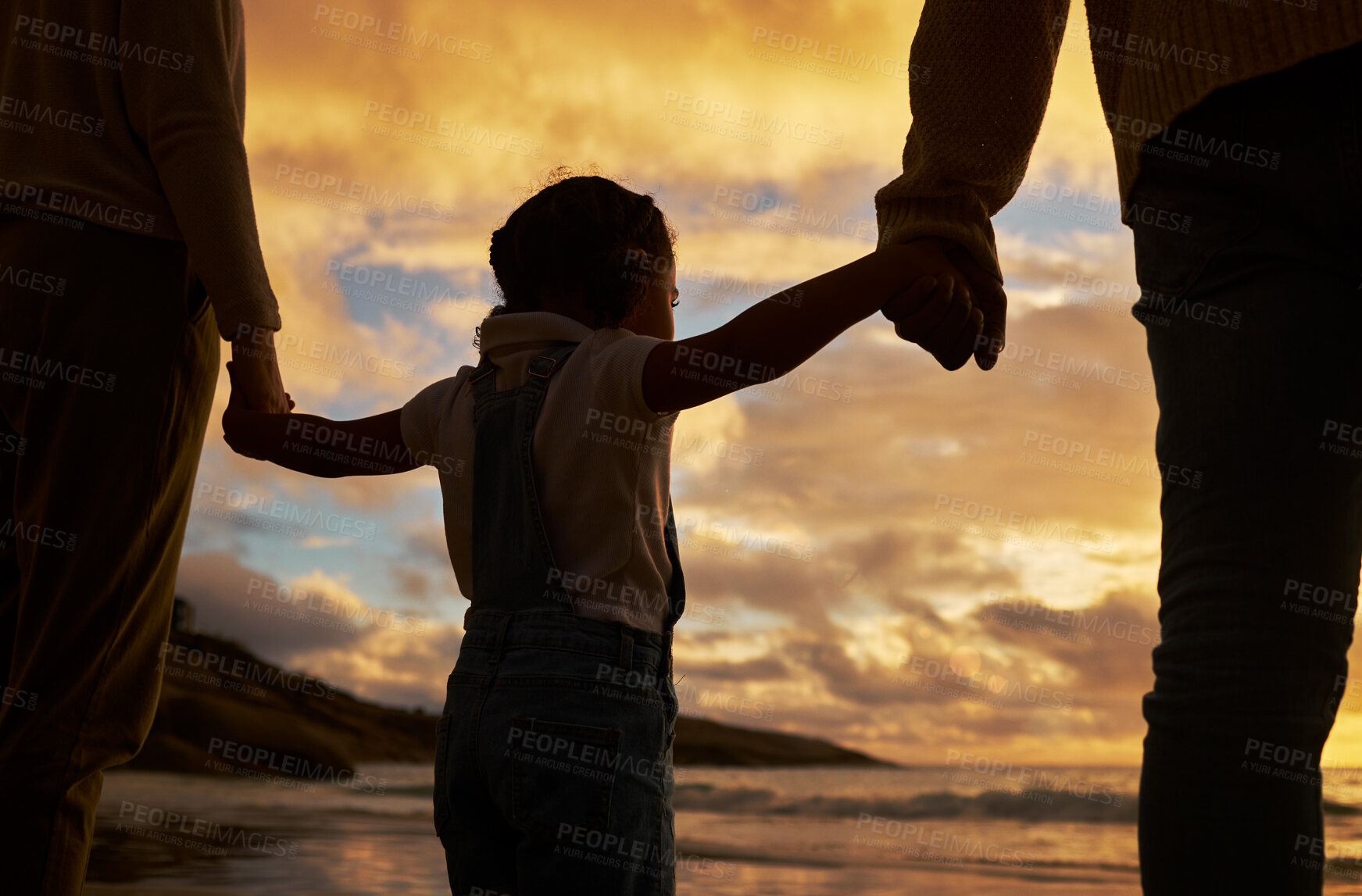 Buy stock photo Parents, child and silhouette of holding hands on the beach during sunset for family bonding in the outdoors. Kid hand, mother and father enjoying the scenic view, care and freedom on the ocean coast