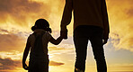 Sunset, silhouette and father holding hands with child at the beach standing together. Love, affection and dad bonding with girl by ocean enjoying holiday, family vacation and weekend in summer