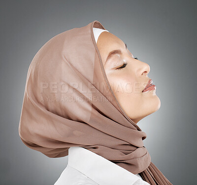 Woman, muslim and beauty in hijab scarf embracing islamic religion against a grey studio background. Beautiful head of female model in islam with calm, peaceful face in modesty or privacy for culture