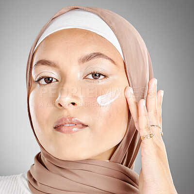 Buy stock photo Muslim, beauty and skincare woman with cream on face product against a grey mockup studio background. Hijab, islam and islamic model face with cosmetics for skin, body wellness and cosmetology 
