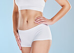 Body, diet and weightloss with a woman in studio on a blue background with her hand on her hip for wellness. Fitness, health and stomach with a model female in underwear for a healthy lifestyle