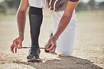 Baseball, sports and athlete tie laces of shoes to prepare for a match or training on an outdoor field. Softball, sneakers and active man getting ready for a game or practice on a sport pitch.