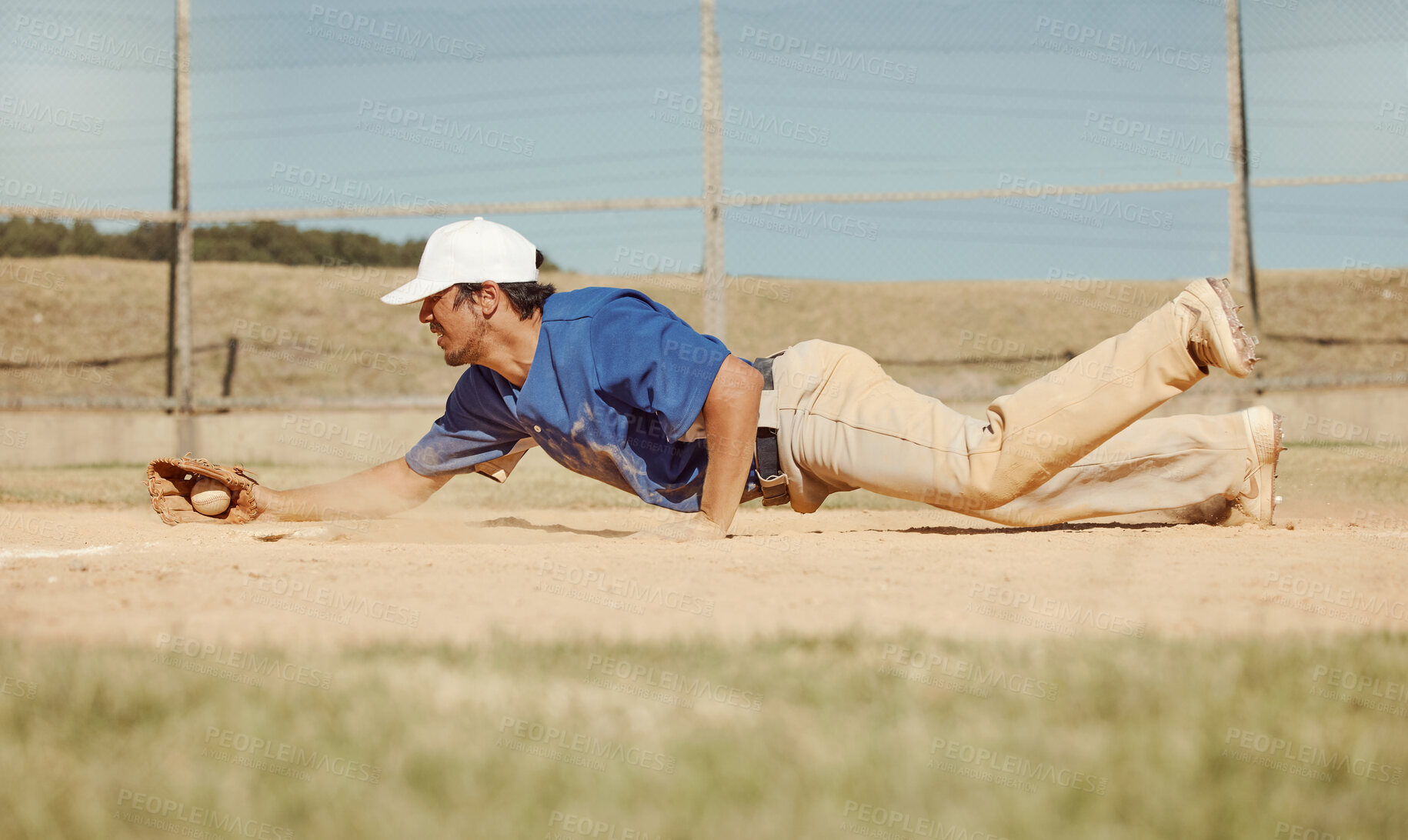 Buy stock photo Sports, action and a man catching baseball, sliding in dust on floor with ball in baseball glove. Slide, dive and catch, baseball player on the ground during game, professional athlete on the field.