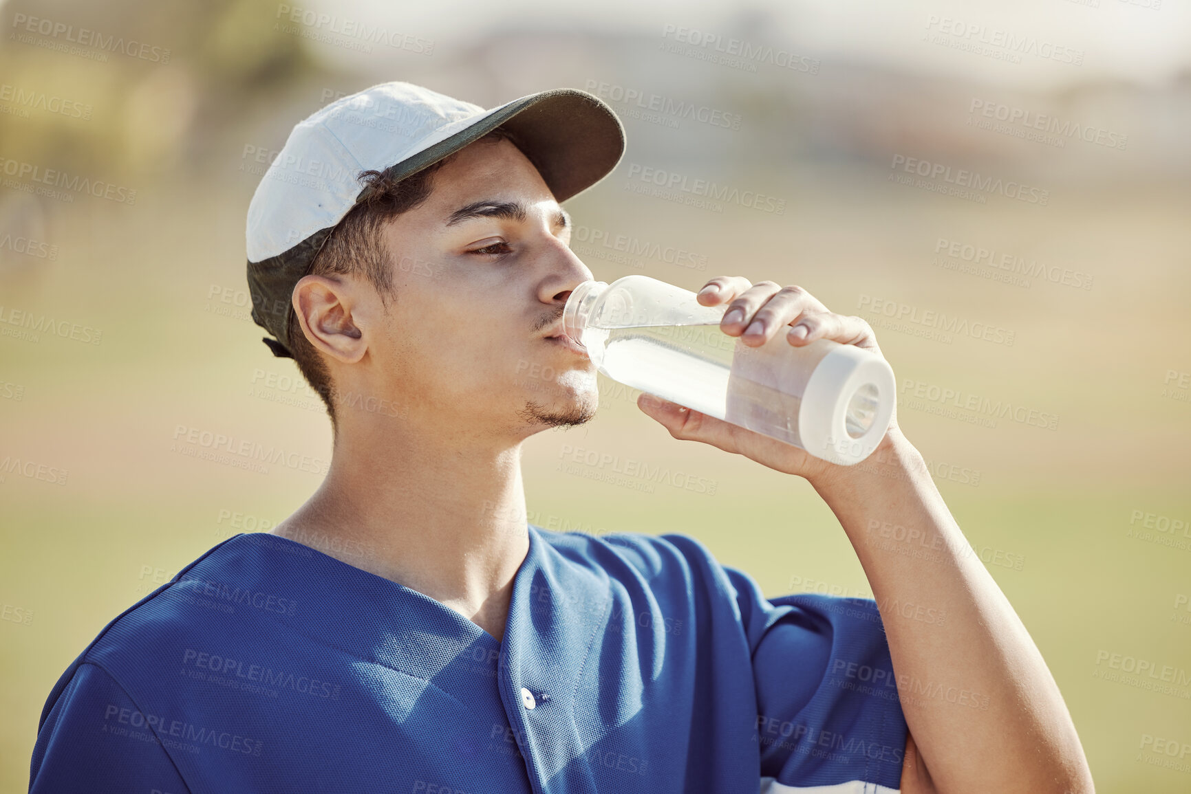 Buy stock photo Fitness, water bottle and athlete drinking liquid for thirst, hydration and health while training. Sport, exercise and baseball player enjoying a refreshing drink while practicing on an outdoor field