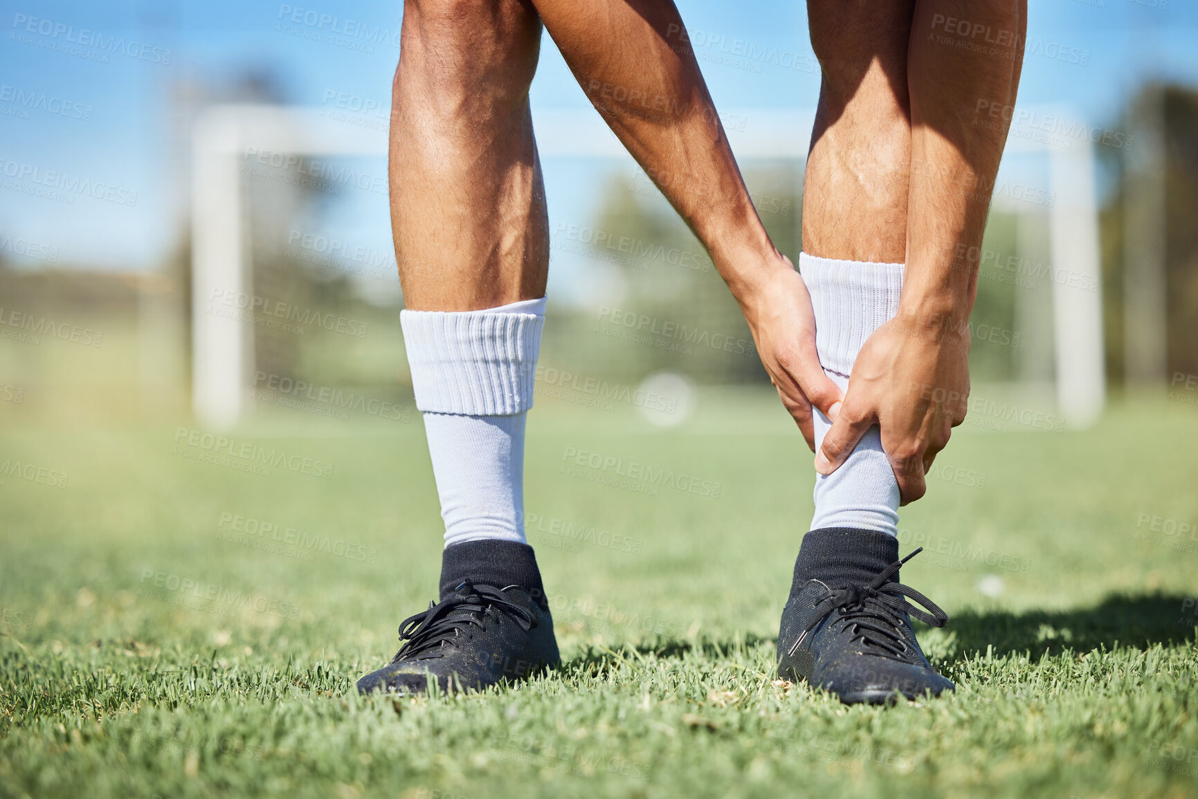 Buy stock photo Sports, soccer and ankle injury on grass with self assessment of physical pain at athlete game. Hurt, injured and joint discomfort of football man on field checking painful leg at competition.

