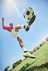 Football, fitness and soccer player training with a juggling exercise on soccer field, grass or football stadium. Sports, jumping and below view of a healthy athlete with skills and creative talent
