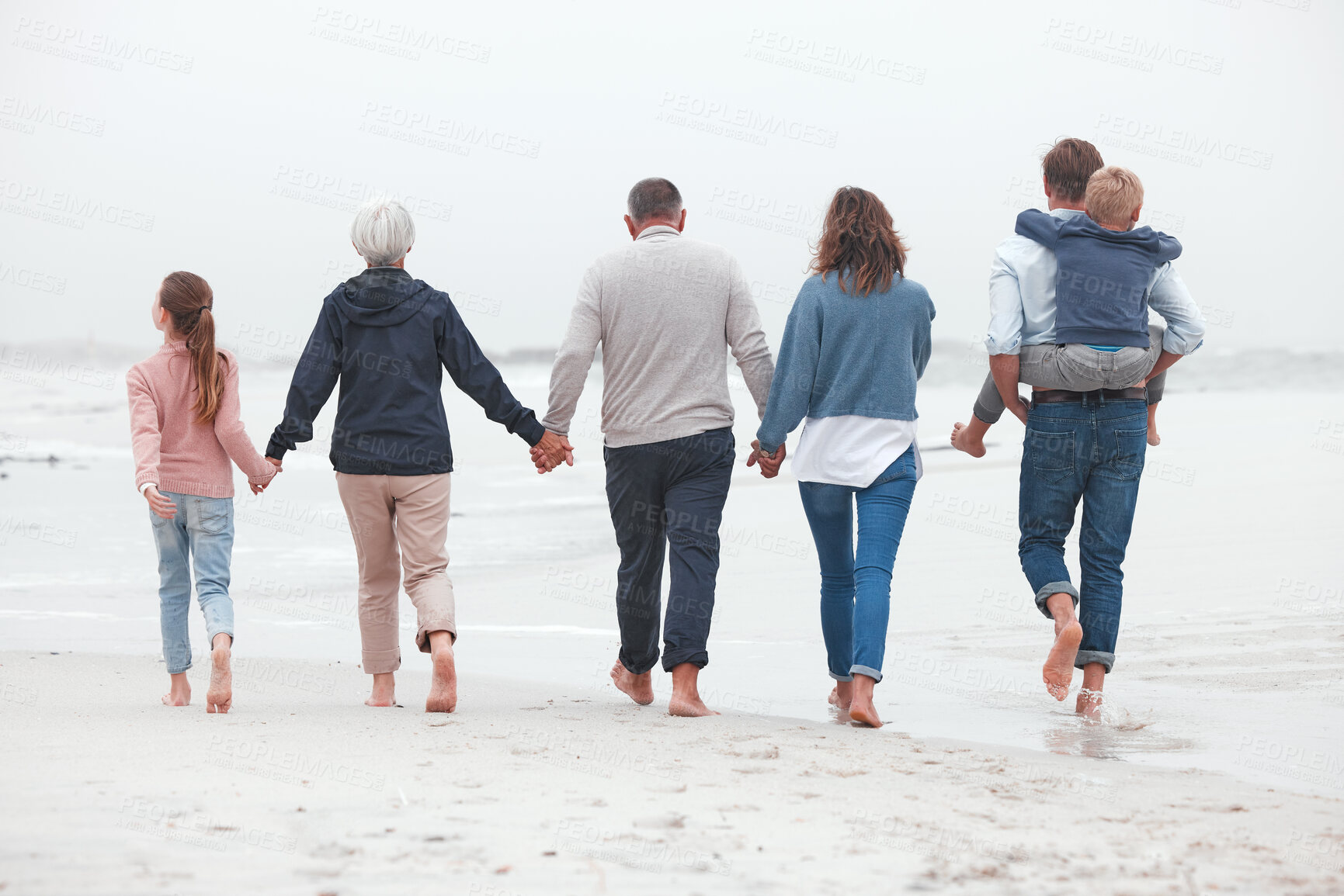 Buy stock photo Holding hands, walking and big family on the beach for exercise while on summer vacation. Grandparents, parents and children on outdoor walk in nature by ocean while on holiday, adventure or journey.