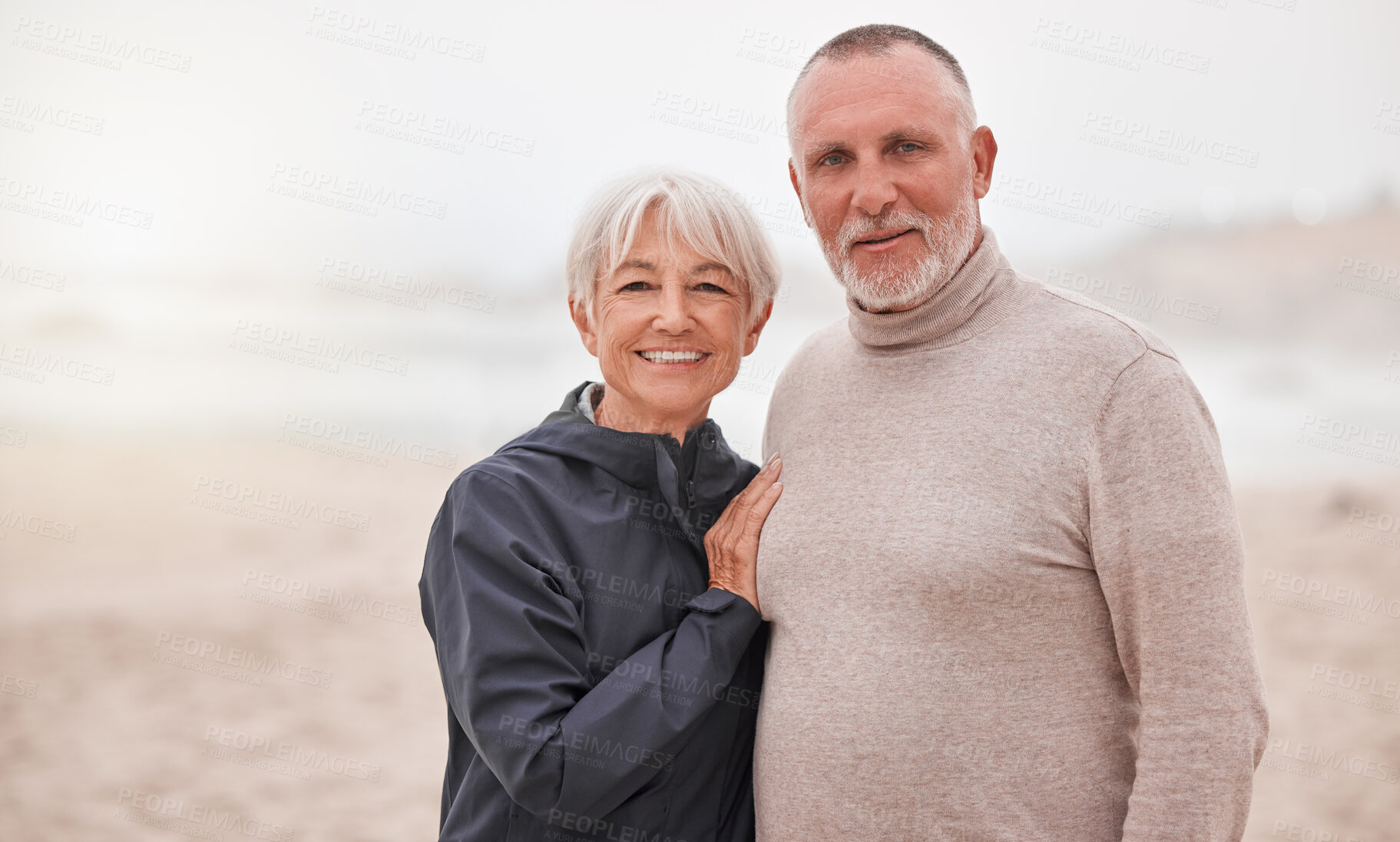 Buy stock photo Portrait of happy and senior couple couple enjoy a romantic date at the beach on a misty day. Love, happiness and elderly retired husband hug wife while seaside retirement vacation or travel holiday 