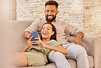 Couple, lounge and phone of people on a house sofa with technology watching a video or funny meme. Streaming, social media and internet scroll of a girlfriend and boyfriend in a living room laughing