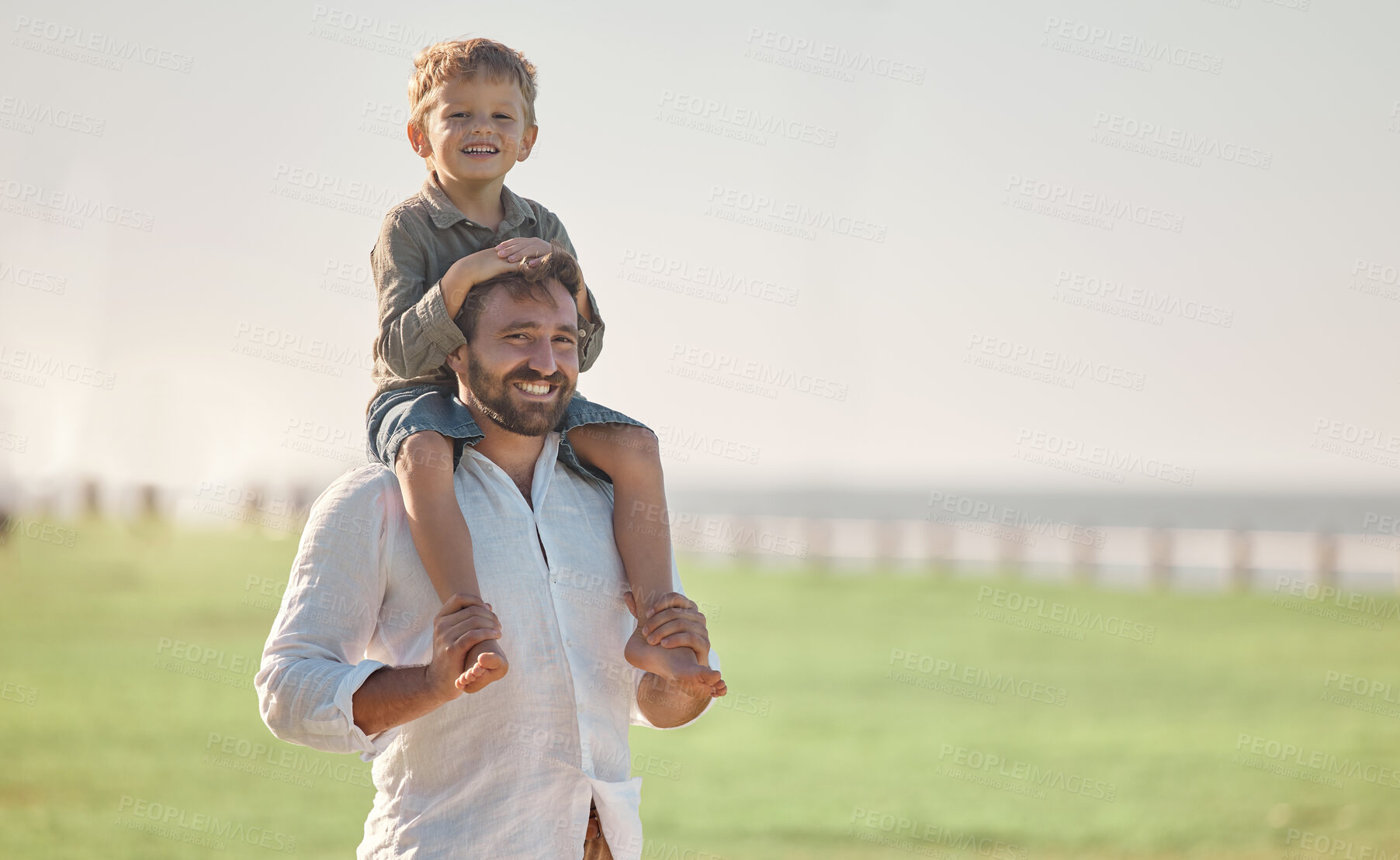Buy stock photo Father, child and summer vacation outdoor in nature for family, love and fun with son on shoulders for happiness portrait. Happy dad man and kid together with smile for time together on grass field
