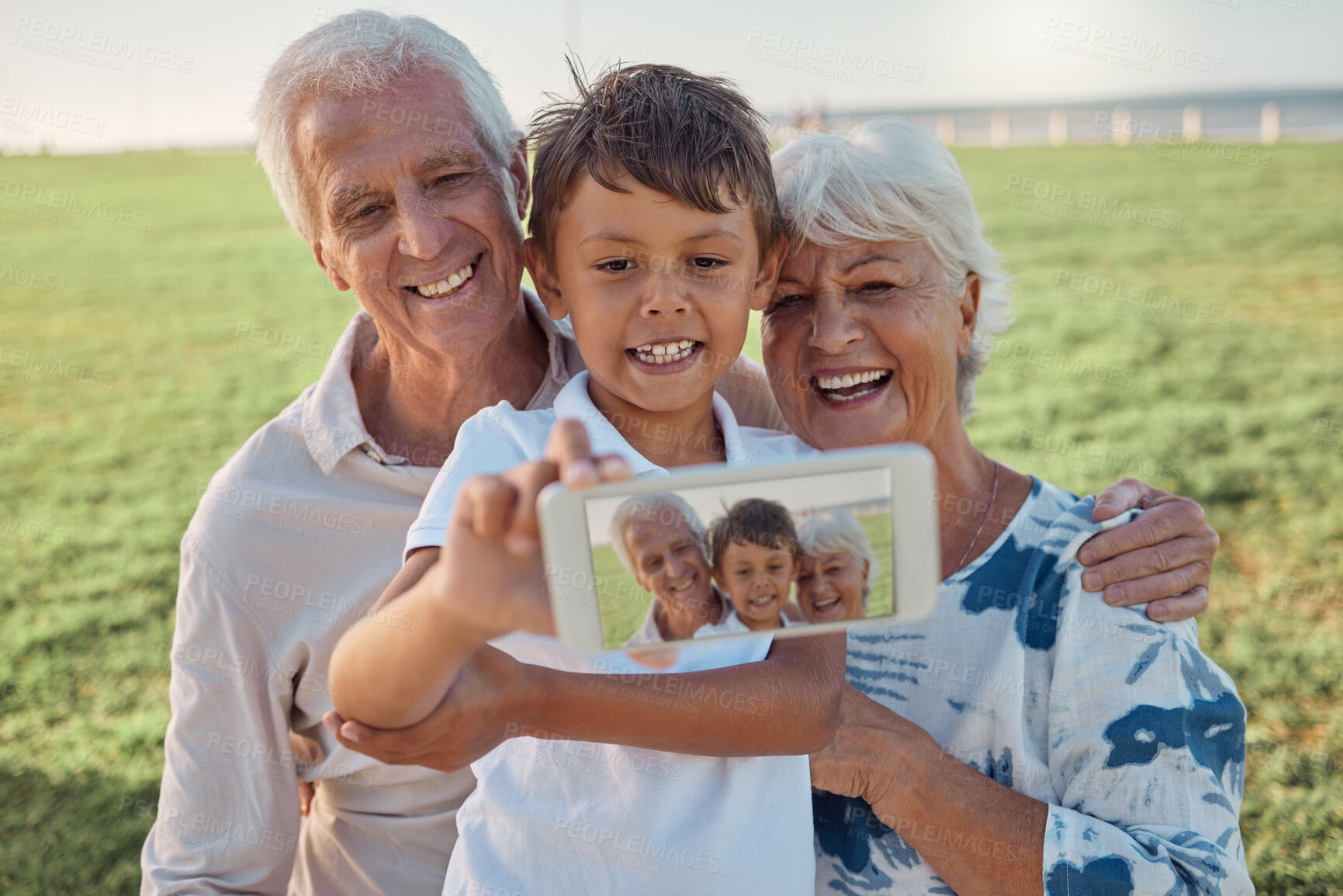 Buy stock photo Phone, selfie and happy grandparents with child outdoor in nature on family picnic together. Happiness, smile and elderly man and woman in retirement taking picture on smartphone with boy grandchild.