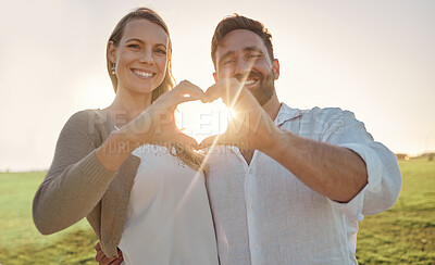 Buy stock photo Couple, portrait and heart hand with sun for romantic date on beautiful field in Ireland. Love, happy and smile of dating people enjoying countryside together with natural sunshine flare.

