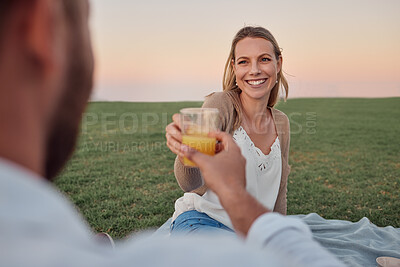 Buy stock photo Toast, juice and couple on a date in a park for love in marriage together during summer. Happy, smile and young woman cheers with a drink and a man on a picnic in nature for happiness and peace