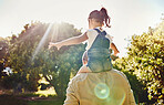 Back, child and father walking in a park for freedom, care and love together in summer. Girl and dad on an adventure walk in nature, garden or backyard while carrying kid on shoulders with flare