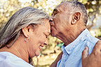 Senior couple, love and forehead kiss for care, passion and embrace for romantic relationship together in nature. Happy elderly man and woman in retirement with smile for romance kissing and hugging