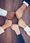 Fist, above and employees meeting with support, partnership and solidarity together at work. Hands of corporate, diversity and motivation from workers in a team for business and goal on a table