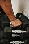 Hand, dumbbell and fitness with a man bodybuilder in a gym for exercise, training or a workout with weights. 