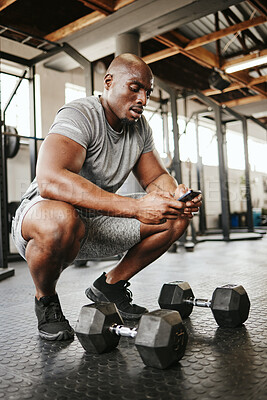 Buy stock photo Fitness, phone and online personal trainer at the gym typing or searching on social media in Nigeria. Strong black man, bodybuilder and healthy sportsman networking or texting a digital message 
