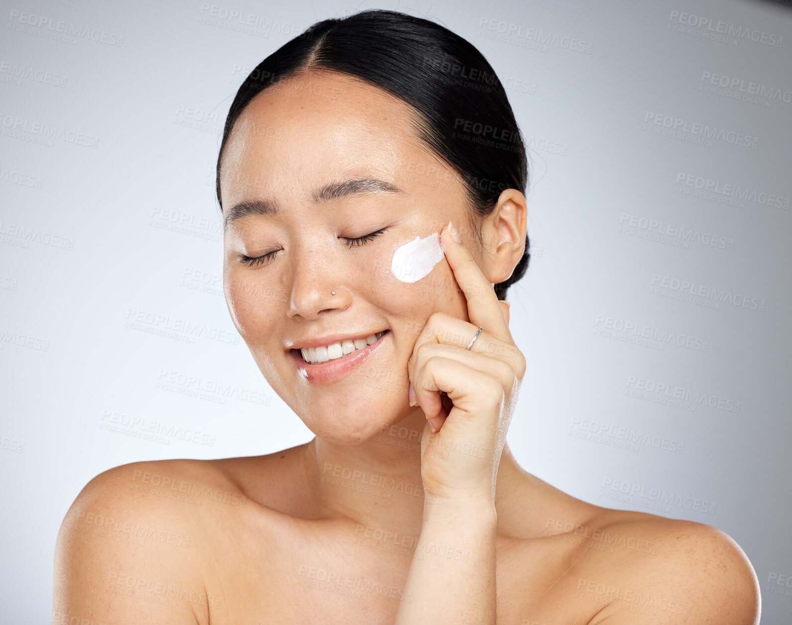 Buy stock photo Asian woman, cream and cosmetics for skincare, wellness and smile with health, natural beauty and studio background. Makeup, young girl and organic facial for treatment, happiness and face care touch