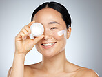 Cream, eye skincare and woman with natural wellness product against grey mockup studio background. Portrait of happy asian beauty model smile with pot of facial makeup lotion with mock up space
