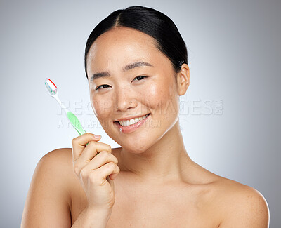 Buy stock photo Beauty, dental care and oral hygiene with an asian woman in studio on a gray background with a smile. Portratit, teeth and toothbrush with a young female brushing her teeth for health or wellness