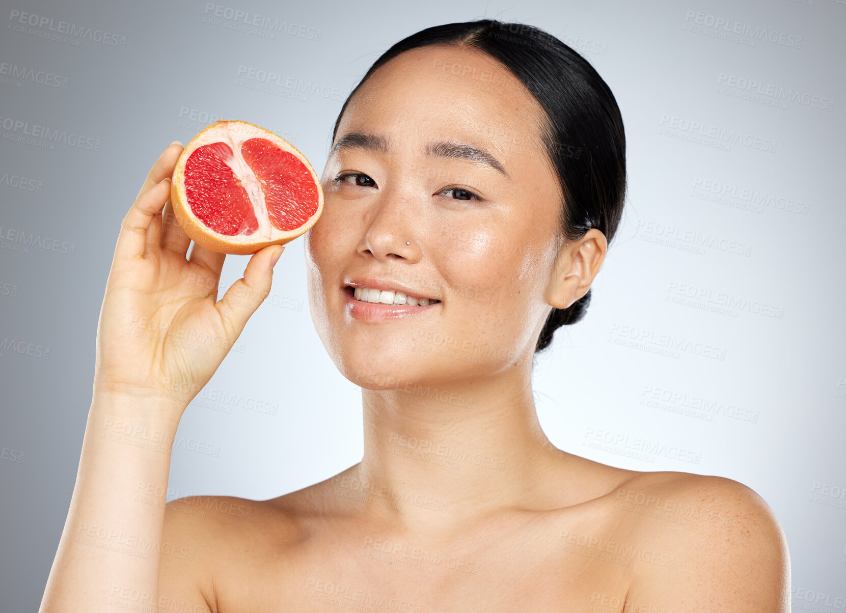 Buy stock photo Grapefruit, skincare and woman with food for face, wellness and beauty against a grey mockup studio background. Portrait of young, happy and Asian model with fruit for nutrition, diet and body health