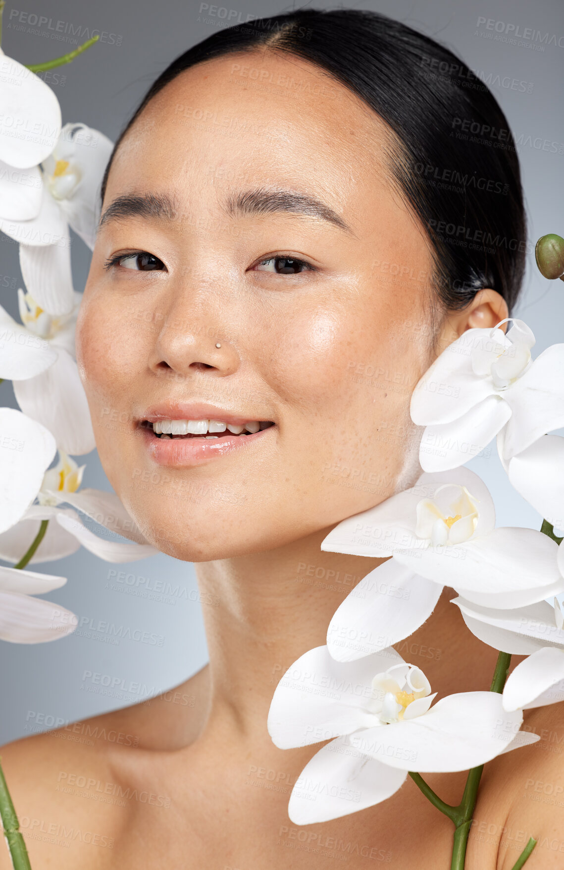 Buy stock photo Beauty, skincare and flowers with a model asian woman posing in studio on a gray background for health or wellness. Face, portrait and natural with an attractive female posing to promote a product