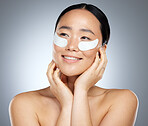 Beauty, skincare and woman using eye patch, face mask or dermatology product against mockup studio background. Happy asian girl model using facial cosmetics on skin for a healthy glow with collagen