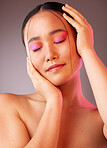 Eyeshadow, asian and beauty woman with hands on face pose with pink and orange cosmetics. Funky, trendy and colorful fashion makeup model for Gen Z cosmetic style on grey studio background.