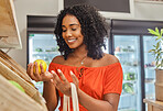 Grocery, shopping and orange with a black woman customer in a produce store for consumerism. Food, supermarket and retail with a female consumer buying fruit from a shelf in an aisle in a shop