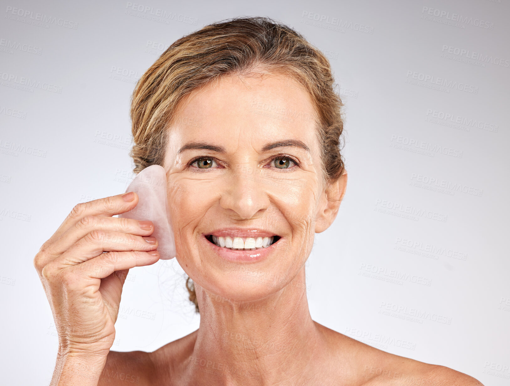 Buy stock photo Face, beauty and senior woman with stone for facial massage on gray studio background. Health, skincare and elderly female model from Canada with rose quartz guasha for anti aging or smooth wrinkles
