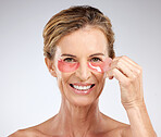 Eye patches, cosmetics and senior woman being happy, smile and wellness with skincare, health and studio background. Portrait, makeup and mature female with organic facial. for eye care and healthy.