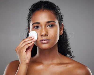 Buy stock photo Beauty, face and cotton pad with a model black woman exfoliating her skin in studio on a gray background. Cosmetics, treatment and skincare with an attractive young female using a natural product