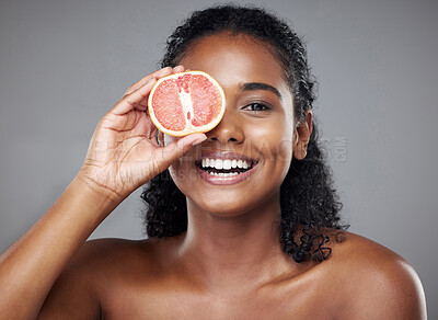Buy stock photo Grapefruit, woman skincare or face with fruit for wellness, health or facial glow on grey studio background. Portrait, happy smile or indian beauty model with vitamin c food product for eyes in hands