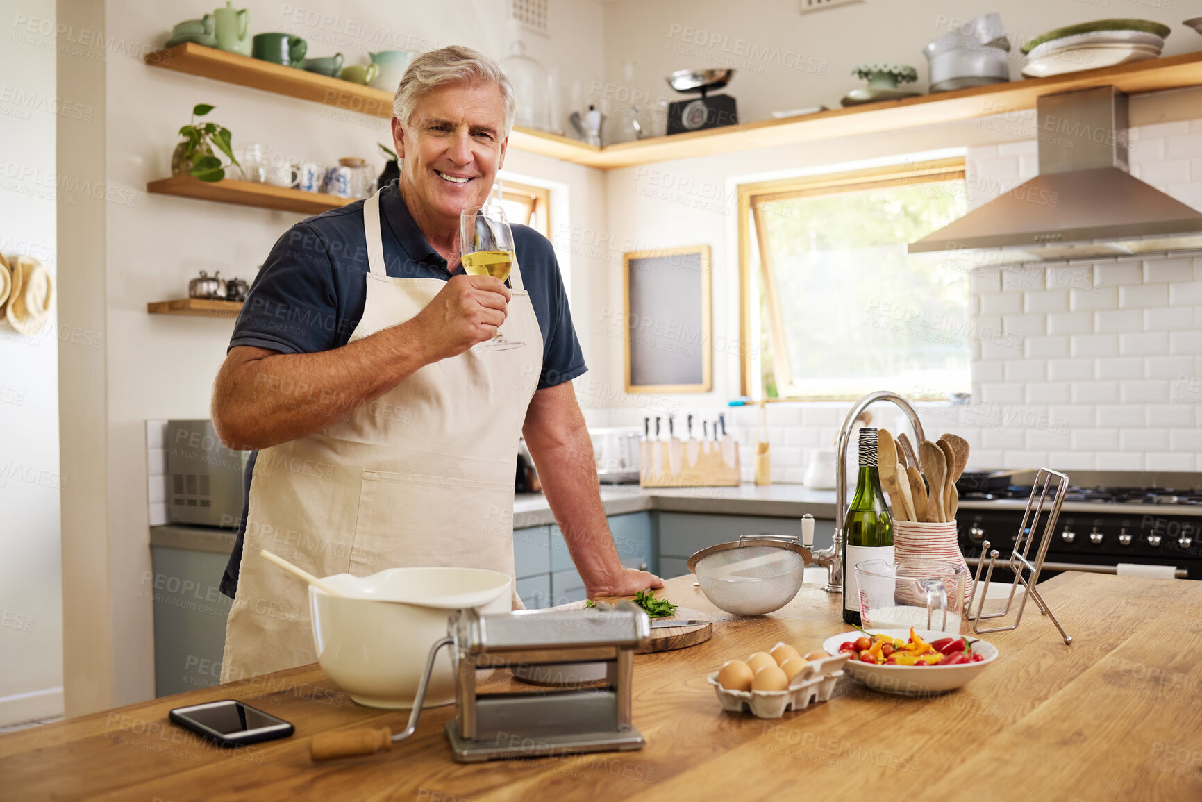 Buy stock photo Elderly man drinking wine while cooking in kitchen for date, dinner or lunch in his home. Happy, smile and senior guy in retirement enjoying glass of alcohol beverage while preparing food at a house.