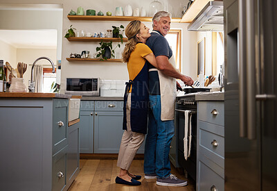 Buy stock photo Senior couple in kitchen hug, cooking healthy food together and care in retirement lifestyle. Elderly man and woman with apron, hugging wife in home or love dinner meal with happy smile in marriage