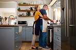 Love, food and elderly couple cooking in a kitchen, hug and bond while preparing a meal in their home together. Happy family, retirement and mature man and woman embrace while preparing a meal 