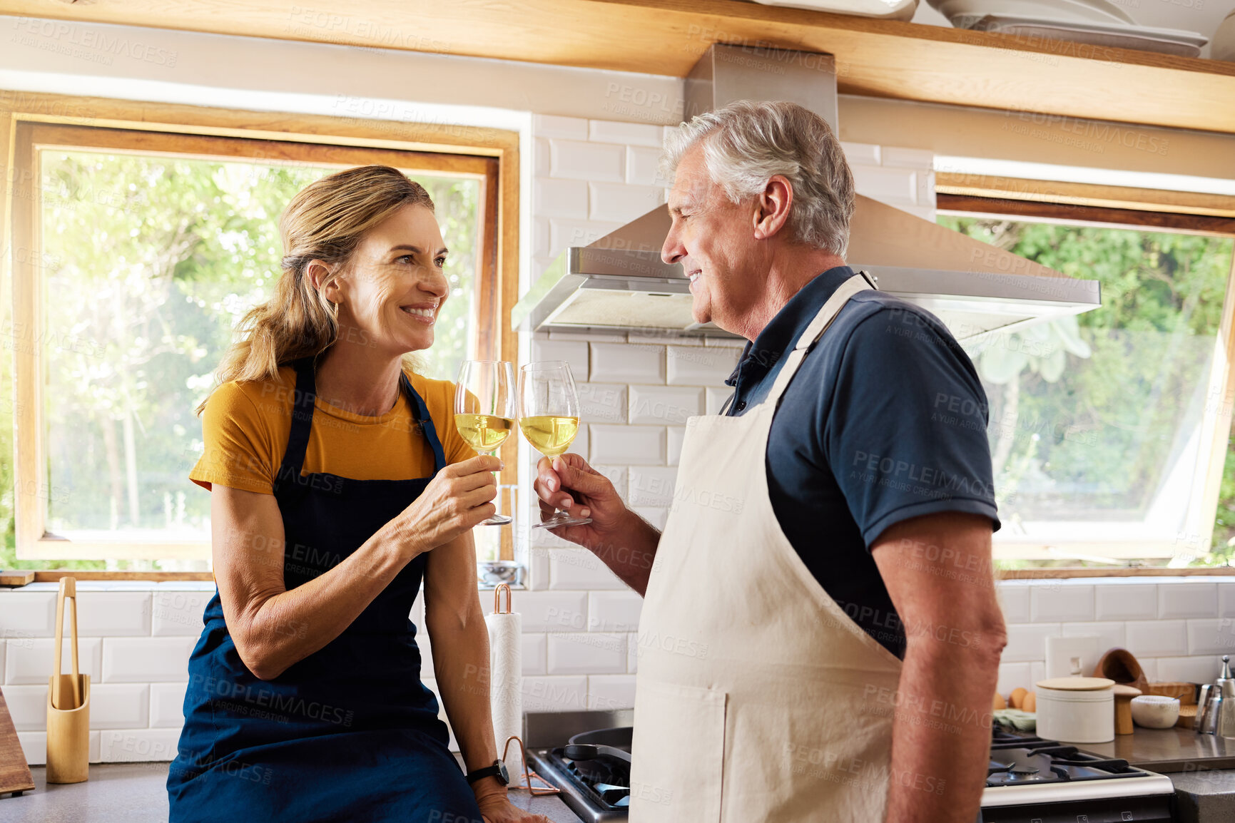 Buy stock photo Wine, cheers and senior couple in the kitchen to cook a mean for date, dinner or lunch at their home. Happy, smile and elderly man and woman in retirement drinking alcohol beverage while cooking food