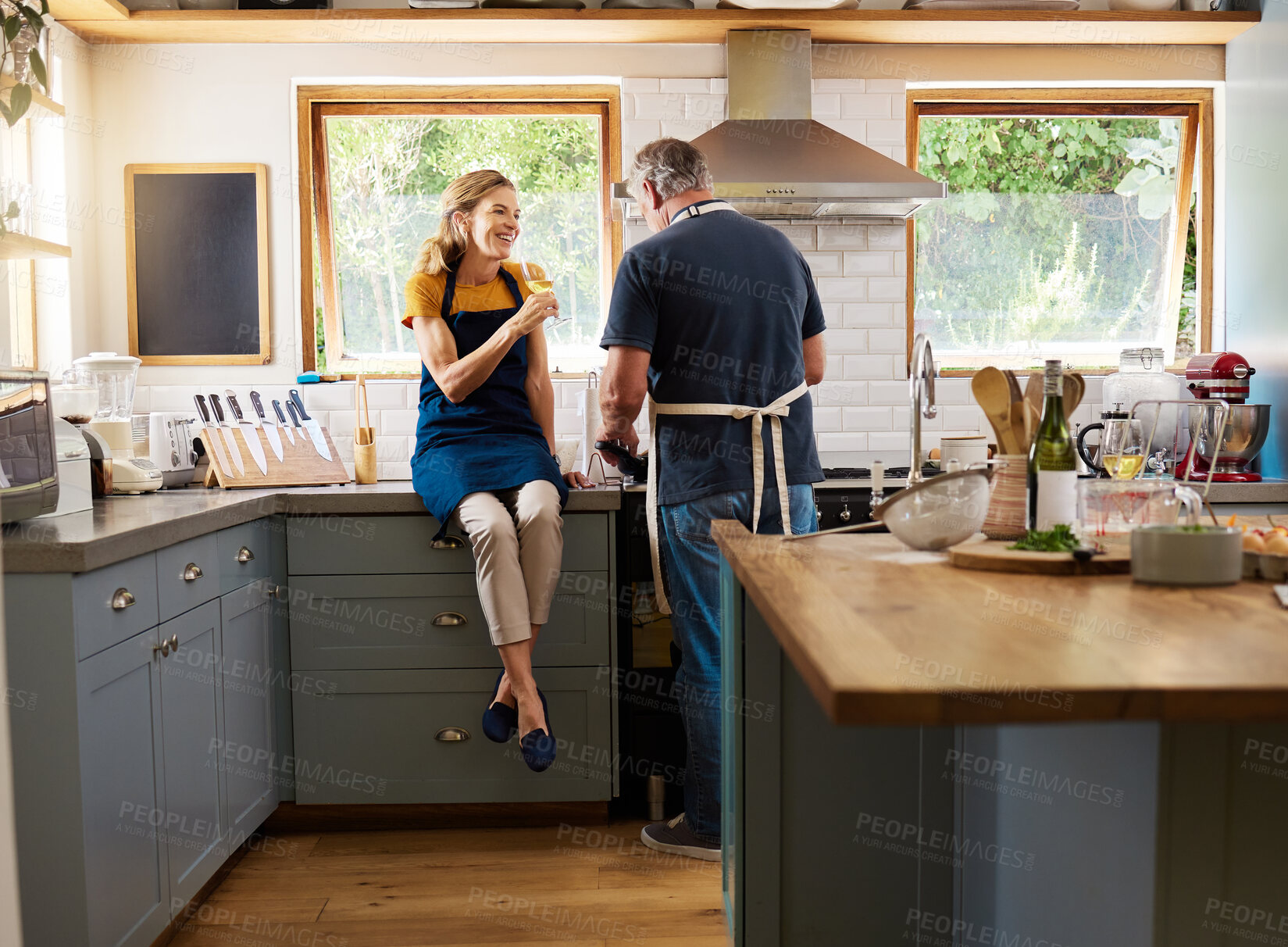 Buy stock photo Couple, wine and cooking in kitchen, happy and talking while bonding, conversation and home. Senior, man and woman in retirement with glass, food and together in house with love, romance and laugh