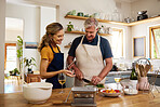 Family, food and elderly couple cooking in kitchen, relax and bond while preparing meal in their home. Love, happy family and retirement with cheerful, elderly and happy man and woman prepare dinner