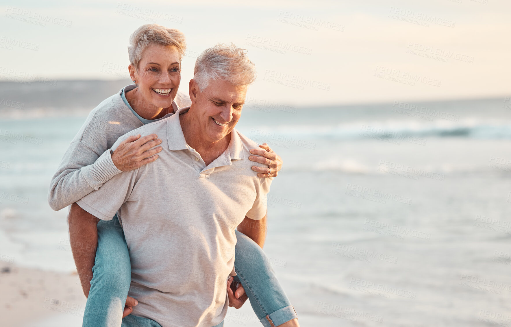 Buy stock photo Love, beach and piggyback with a senior couple walking by the sea or ocean while on a date in summer together. Nature, earth and water with an elderly man and woman pensioner taking a walk on a coast