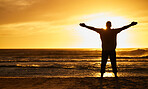 Silhouette of man with view, sunset and beach with arms out by the ocean, carefree and peace, freedom on vacation outdoor. Free, sunshine and hands up, travel and adventure in nature, sea water.