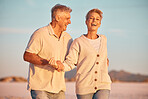 Retirement, couple and with smile outdoor, walking and being loving together for marriage, relationship and happy. Love, senior man and mature woman being playful, embrace and holding hands on sand.