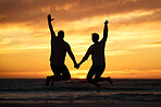 Couple, sunset and jump at beach while holding hands for happiness, bonding or romance on vacation. People, love and happy by sea, ocean or dusk in evening, sunshine or silhouette on holiday together