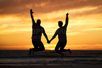 Buy stock photo Couple, sunset and jump at beach while holding hands for happiness, bonding or romance on vacation. People, love and happy by sea, ocean or dusk in evening, sunshine or silhouette on holiday together